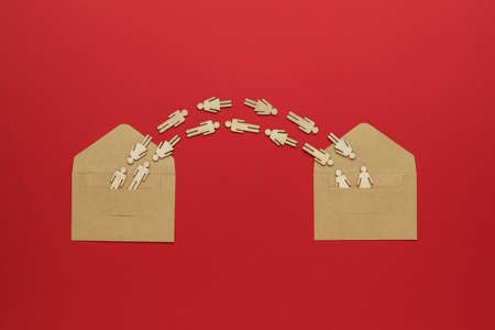 Figures of people flying between two open envelopes on a red background. The concept of...
