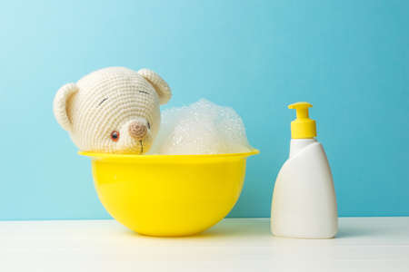 A bathing knitted bear and a bottle of detergent. The concept of bathing small children.の写真素材