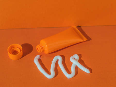 An orange tube and squeezed cream on an orange background. Cosmetic creams.の写真素材