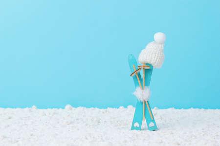 Skis stuck in the snow with sticks and a winter hat on a blue background. Winter sports.の写真素材