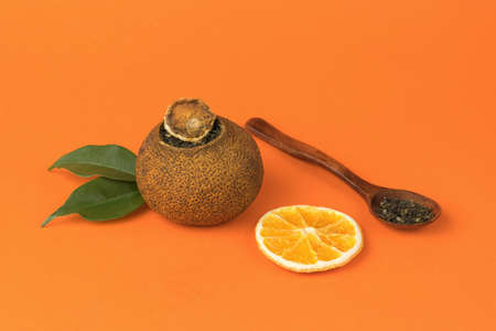 Dried oranges tea and a wooden spoon on an orange background. Tea drink with citrus fruits and fruits.の写真素材