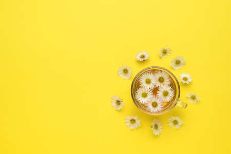 A cup of floral tea and scattered flowers on a yellow background. Medicinal tea. Space for text.の写真素材