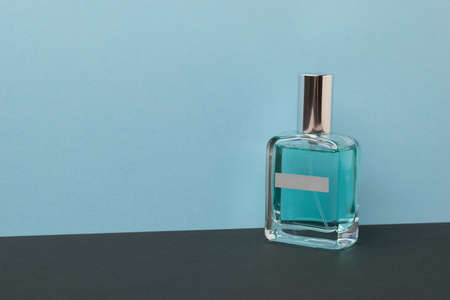 A bottle with blue perfume on a black and blue background. The concept of natural cosmetics.