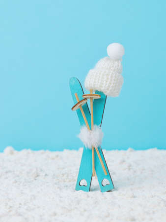 White knitted hat wearing wooden skis on snow on a blue background. Winter sports.