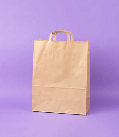 A paper shopping bag on a lilac background. Eco-friendly shopping container.の写真素材