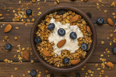 Yogurt, muesli, nuts and blueberries in a bowl on the table. Healthy vegetarian breakfast. Flat lay.