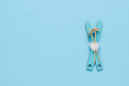 Wooden skis and poles on a blue background. Space for text. Winter sports. Flat lay.