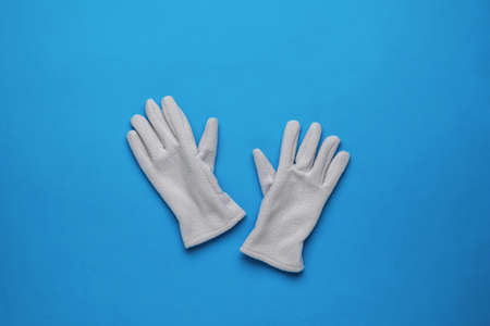 Warm fleece women's gloves on a blue background. A stylish accessory for cold weather. Flat lay.