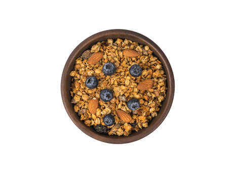 Clay bowl filled with muesli, berries and nuts isolated on a white background. Healthy vegetarian breakfast.の写真素材