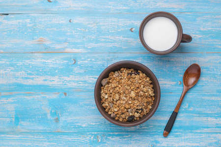 Muesli and milk in pottery on a wooden background. Healthy vegetarian breakfast. Flat lay.の写真素材