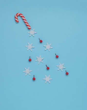 Snowflakes and sweets flying out of a Christmas stick on a blue background. Minimalism. Contemporary art. The concept of the New Year.の写真素材