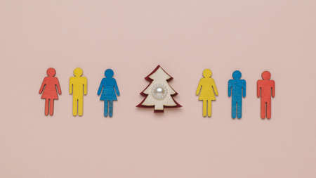 A row of colorful figures of people and a Christmas tree on a pastel background. The minimum concept...