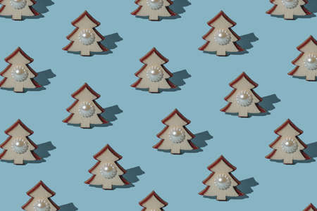 A pattern of small wooden fir trees with decorations on a blue background. The minimum concept of the New Year. Christmas tree. Contemporary art.の写真素材