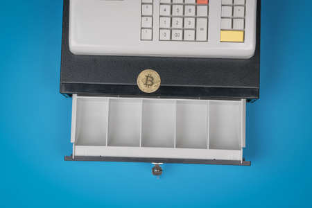 Digital coin on an open cash register on a blue background. The concept of replacing money with digital currency. Virtual space.の写真素材