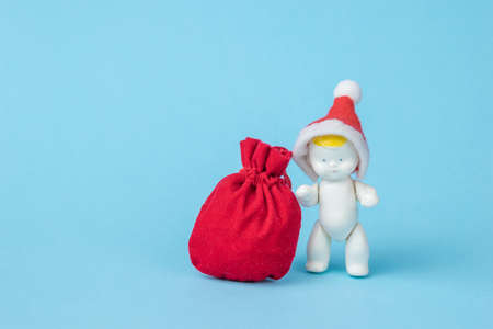 A figurine of a baby in a red hat and a bag with gifts on a blue background. Minimalism. The concept of the new year.の写真素材