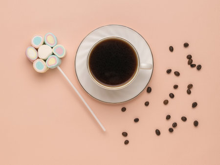 A set of marshmallows on a stick, coffee in a cup and scattered grains on a pastel background. The concept of a fun breakfast. Happy morning. Flat lay.の写真素材