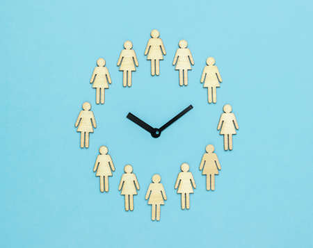 Analog clock made of female figures on a light blue background. The concept of periodic generational change. Flat lay.の写真素材