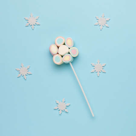 A set of marshmallows on a stick on a blue background with snowflakes. The idea of a festive sweetness.の写真素材