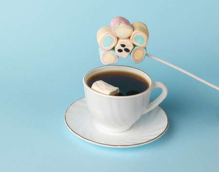 A set of marshmallows on a stick with a painted face and one piece dropped into the coffee. The concept of a fun breakfast. Happy morning.の写真素材