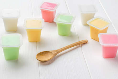 Cups with multicolored yogurts on a white wooden table. Natural healthy food. Fruit and milkshakes.の写真素材