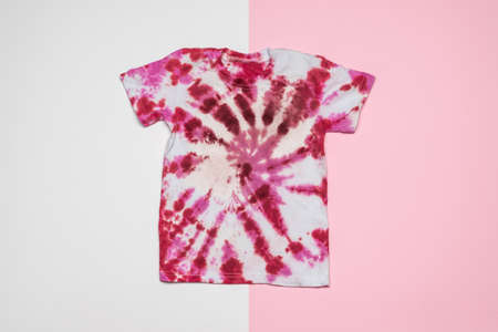 Red and white tie dye T-shirt on a pink and white background. Coloring clothes by hand at home. Flat lay.の写真素材
