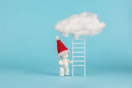 A figure of a baby in a hood near the stairs leading to the clouds. The concept of surprises from Santa Claus. The trend of the New Year. Minimalism.の写真素材