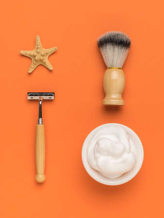 A starfish and a stylish shaving kit on an orange background. Men's accessories for appearance care. Flat lay.の写真素材