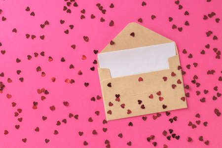 An open postal envelope with a piece of paper and a lot of small red hearts. The concept of Valentine's Day. Flat lay.の写真素材