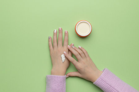 A girl with beautiful makeup is applying cream to her hands from a jar. The concept of using cosmetics. Flat lay.の写真素材