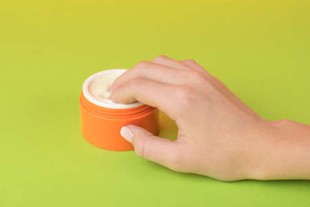 The girl dipped her fingers into the jar of cream. The concept of using cosmetics.の写真素材