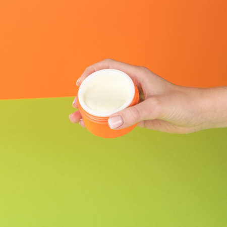 The girl's right hand holding an open jar of cream. The concept of using cosmetics.の写真素材