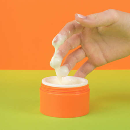 The cream drips from the girl's hand into a jar. The concept of using cosmetics.の写真素材