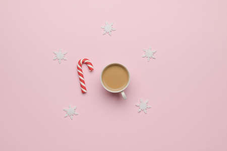 A cup of coffee and a red and white candy on a pastel background with snowflakes. The concept of winter holidays.の写真素材