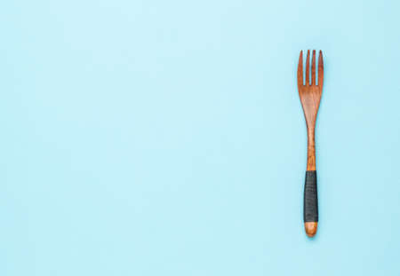 Vintage wooden fork with rope on the handle on a blue background. A place for your text.