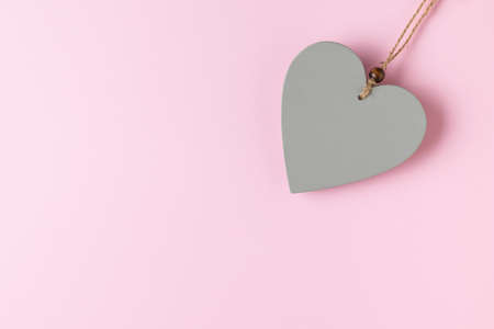 Gray wooden heart on a rope on a pink background. Space for text. The concept of Valentine's Day.の写真素材