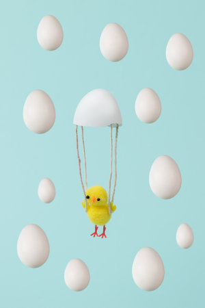 Yellow chicken flying on a parachute from a shell and falling eggs. Easter concept.
