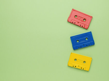 Three multi-colored tape cassettes on a light green background. vintage style in sound recording....