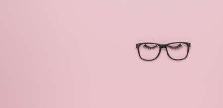Black glasses and big black eyelashes on a pink background. minimalism. flat lay.