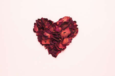 A beautiful heart made of dried rose petals on a pastel background. The concept of a romantic relationship. flat lay.の写真素材