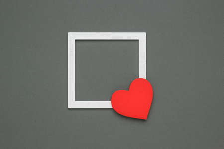 A white frame and a bright red heart on a gray background. The concept of Valentine's Day. flat lay.の写真素材