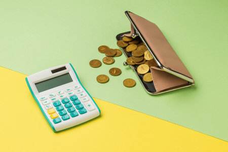 Calculator and wallet with coins on a yellow and green background. The concept of the family budget.