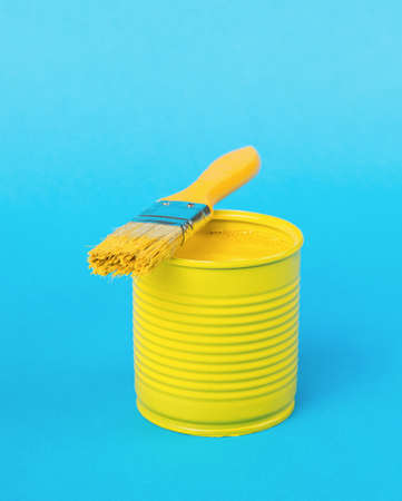 A brush lying on a jar with yellow paint on a blue background. Trending colors. Minimal concept of interior selection.の写真素材