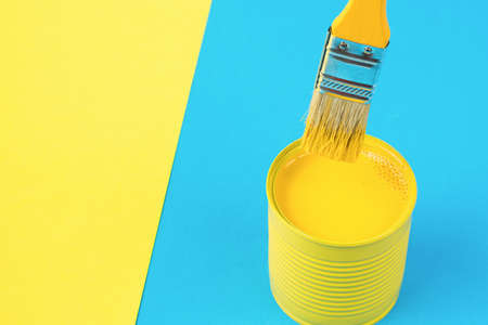 A yellow brush in a jar with yellow paint on a yellow-blue background. Trending colors. Minimal concept of interior selection.の写真素材