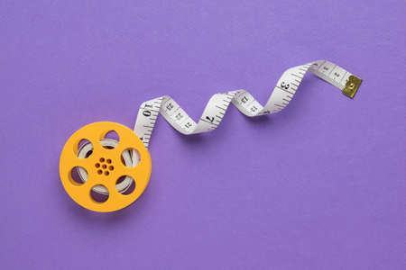 Measuring tape on a yellow coil on a purple background. A device for measuring body parameters. flat lay.の写真素材