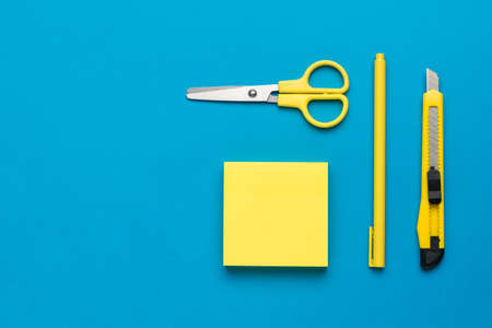 A set of stylish yellow stationery on a blue background. The concept of creativity and education. flat lay.の写真素材