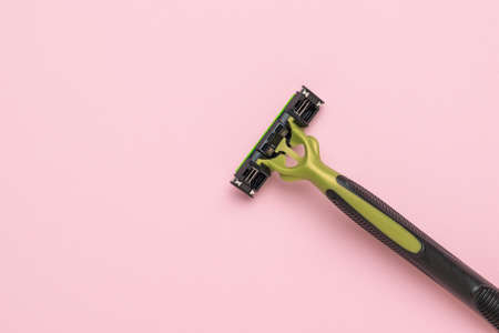 Stylish men's black and green razor on a pink background. The concept of caring for a man's face....