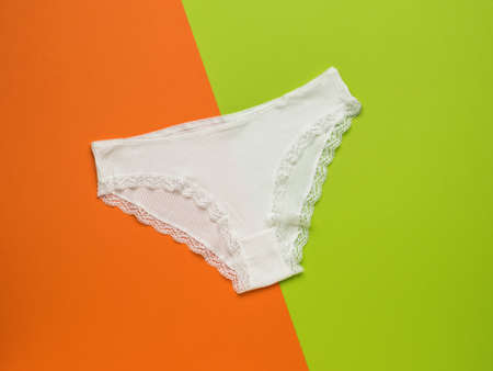 White lace women's panties on an orange and green background. Women's underwear. flat lay.の写真素材