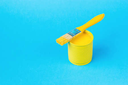 A yellow brush on a jar with yellow paint on a large blue background. Trending colors. Minimal concept of interior selection.の写真素材
