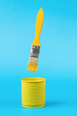 A brush with dripping paint over a jar on a bright blue background. Trending colors. Minimal concept of interior selection.の写真素材
