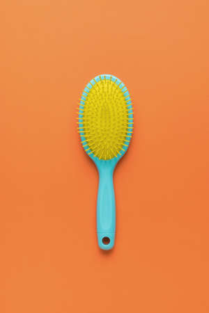 A bright yellow-blue combo on a bright orange background. A device for combing hair.